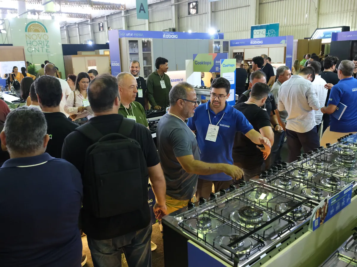 Lojistas em volta dos cooktops expostos num estande
