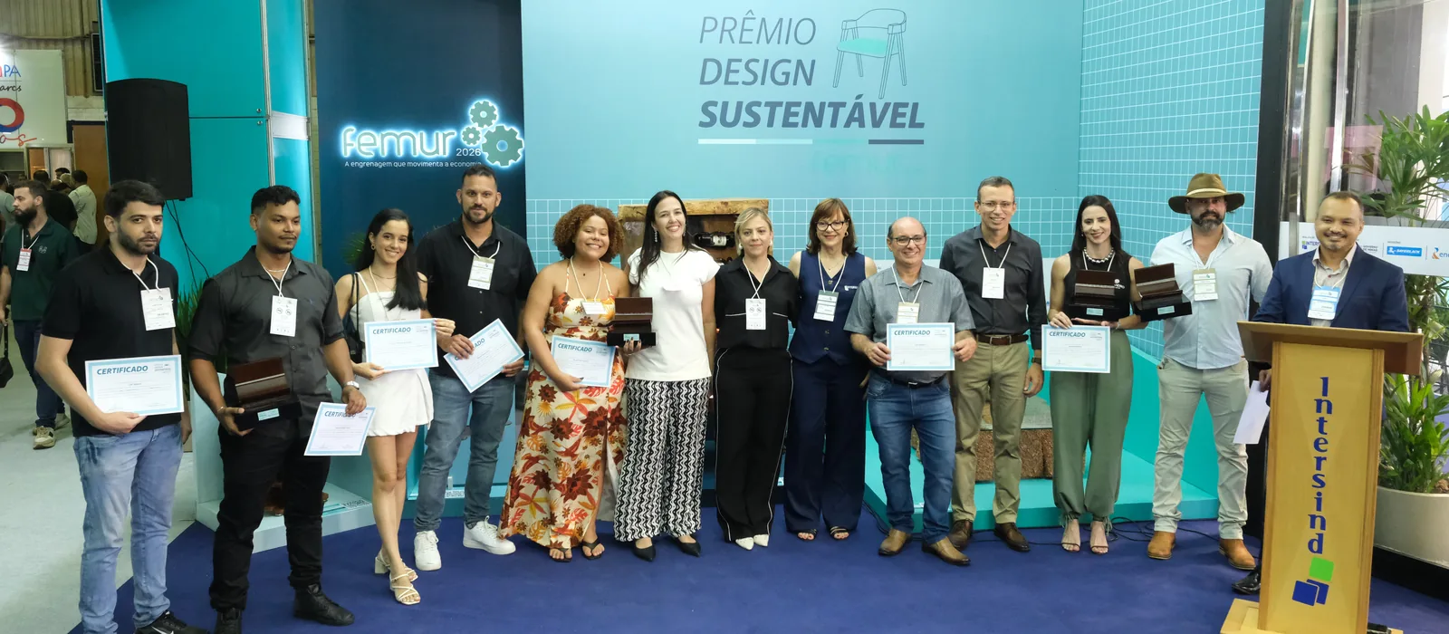 Os premiados do Prêmio Design Sustentável 2026 reunidos no estande do Prêmio, com o púlpito do Intersind